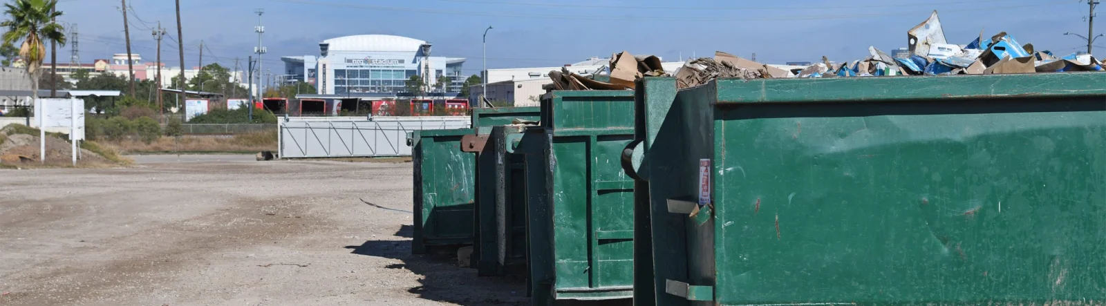 Roll-off containers at the Houston waste facility, with NRG Stadium in the background